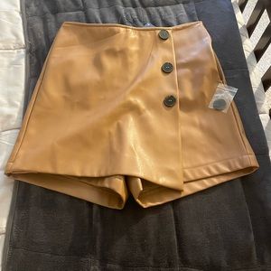 Camel colored skort. Not real leather, feels vinyl-y. Zipper side fake buttons